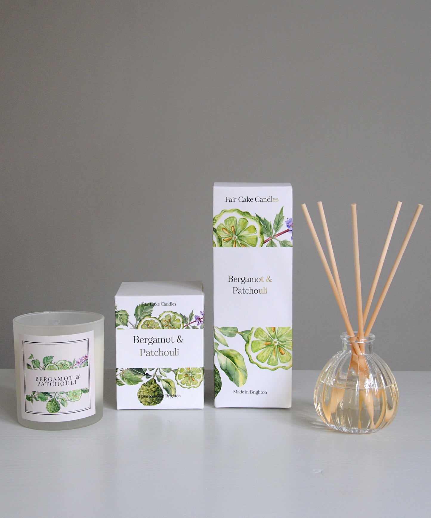 Bergamot and Patchouli candle, diffuser, and packaging on a gray background