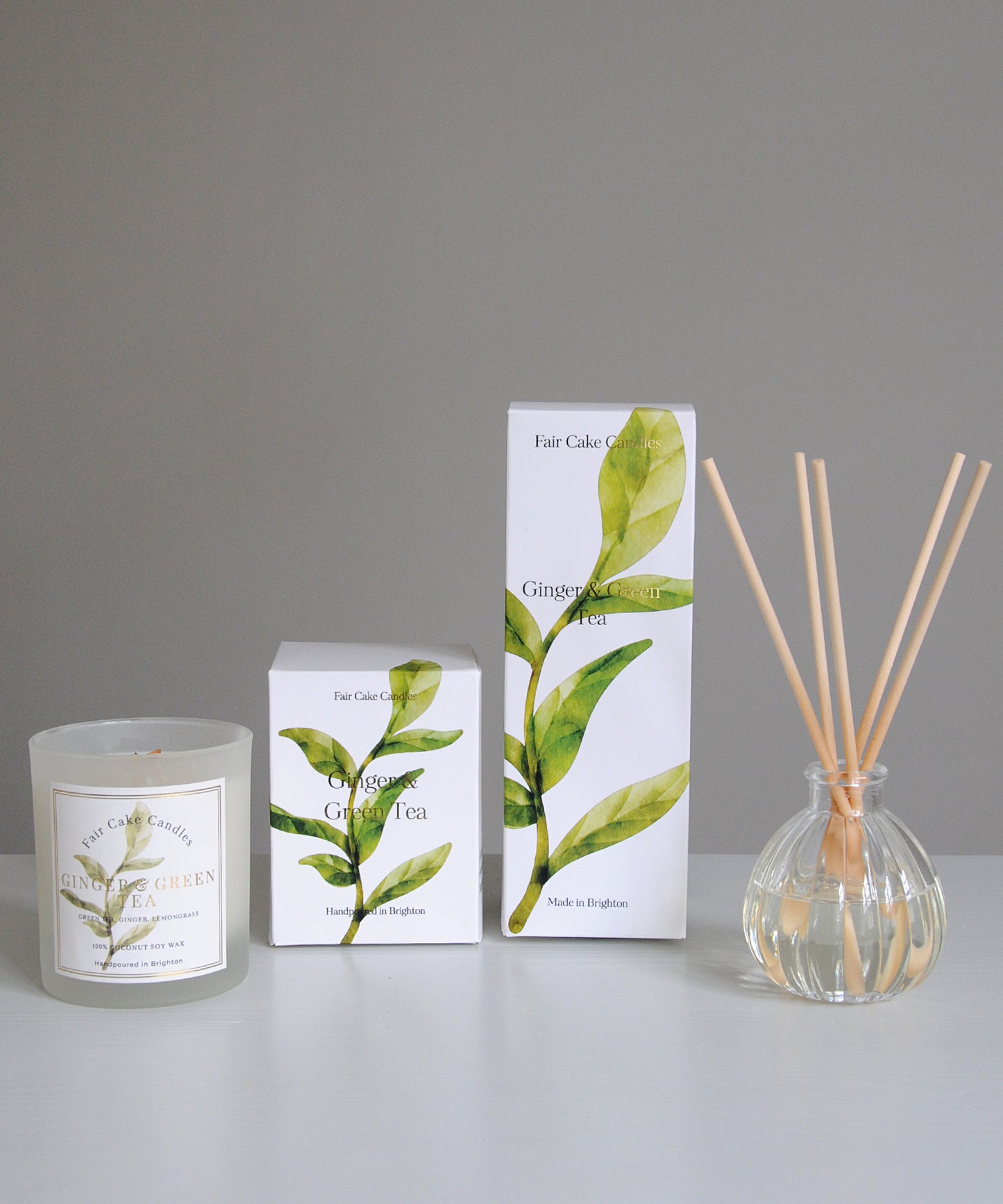 Candle, packaging, and diffuser with green leaf design on a gray background