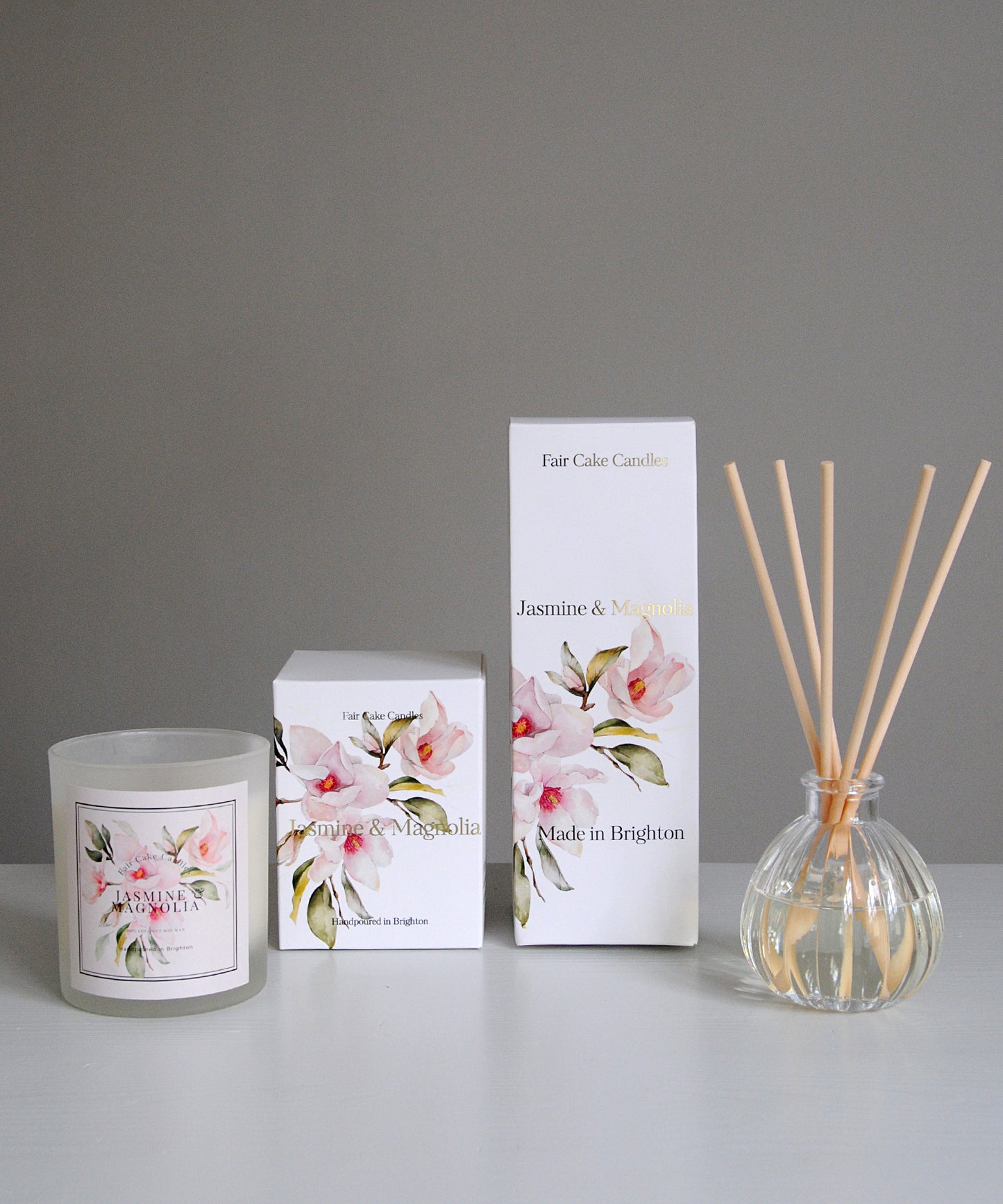Candle, box, and diffuser with floral design on a gray background