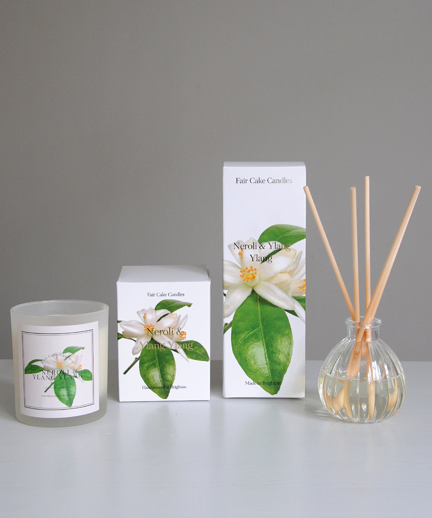 Candle, packaging, and diffuser with floral design on a gray background