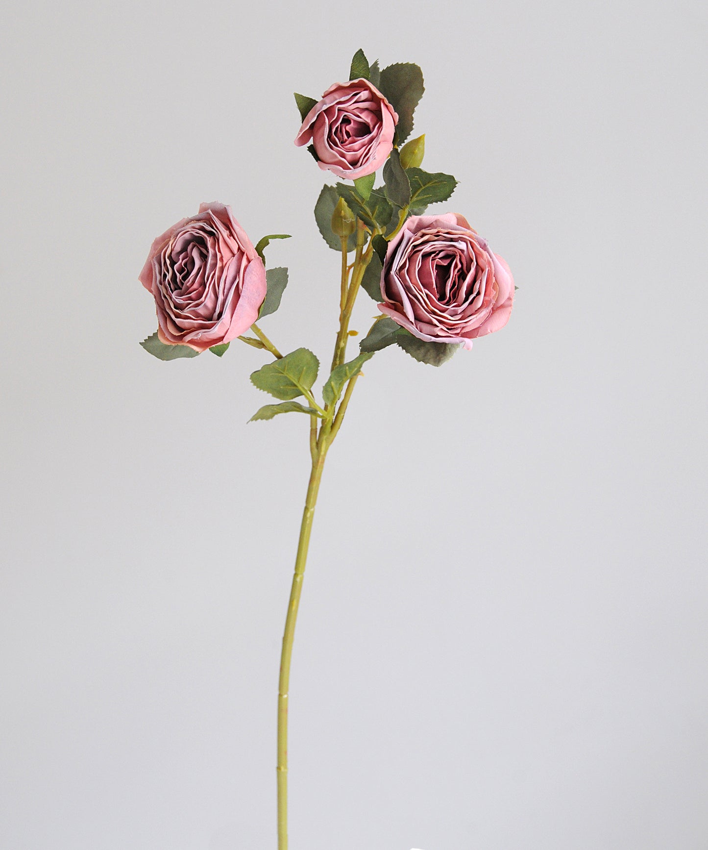 Artificial flower stem with pink roses on a light gray background