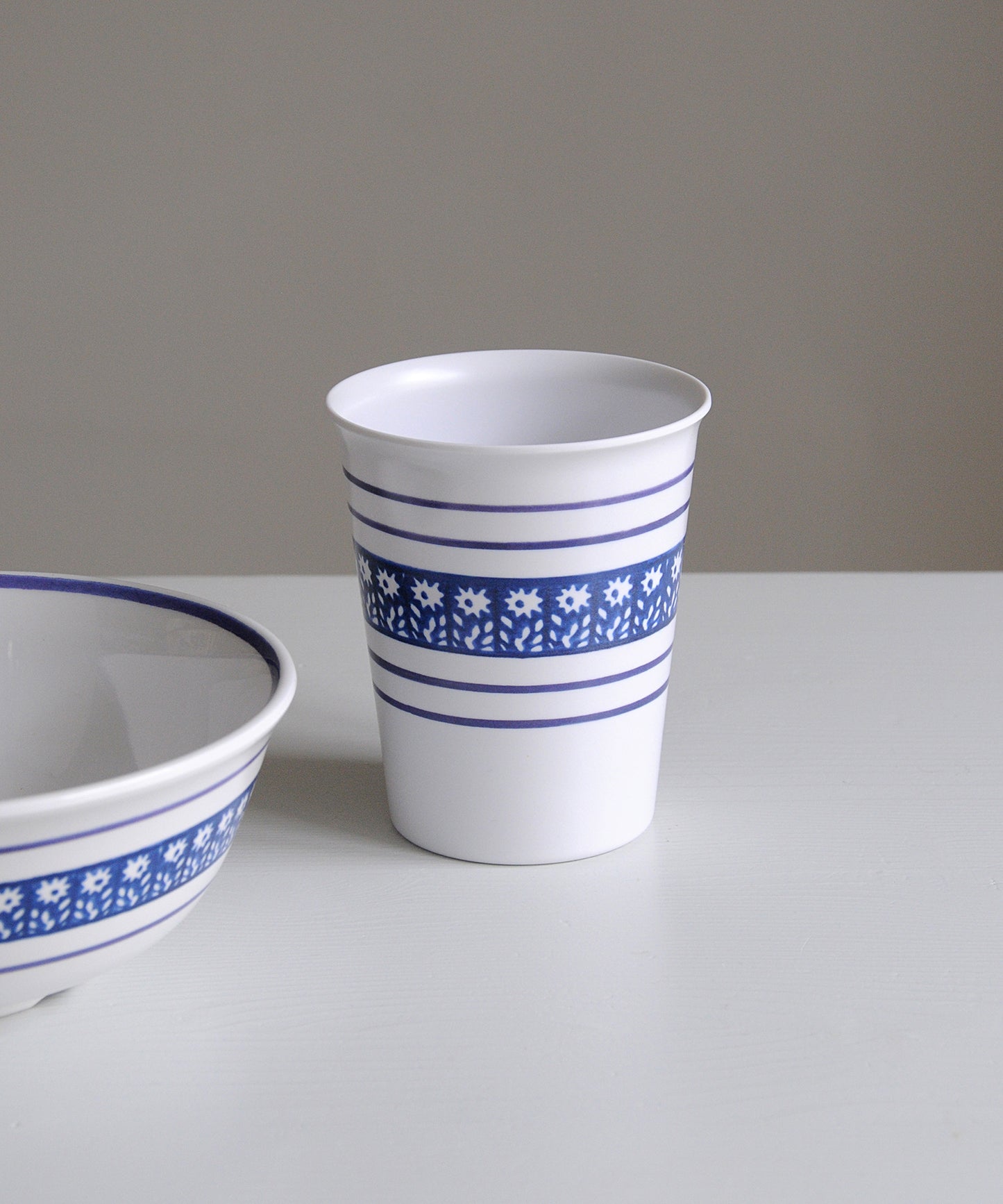 White cup and bowl with blue floral patterns on a white surface and gray background