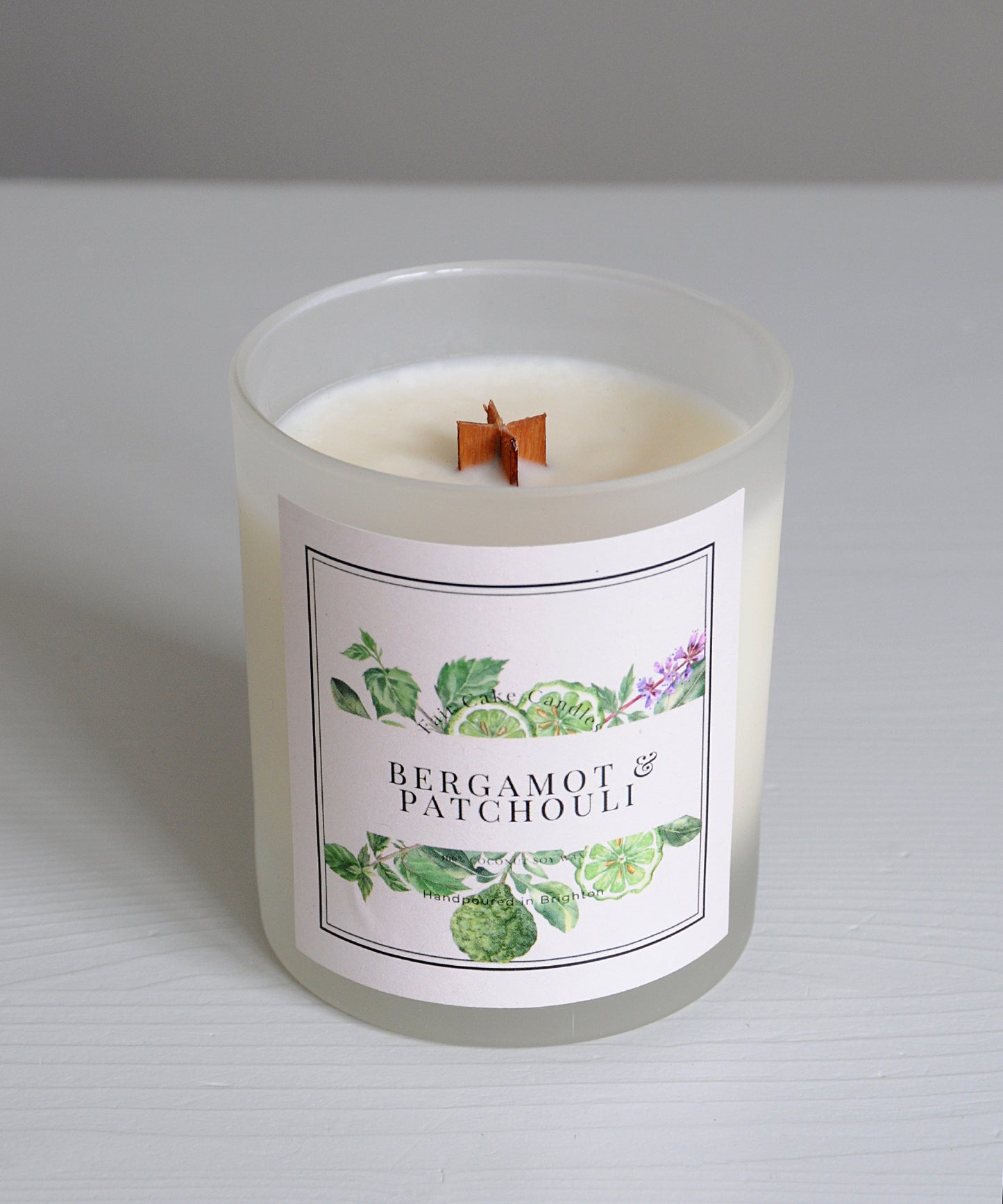 Candle with a label featuring bergamot and patchouli scents on a white background