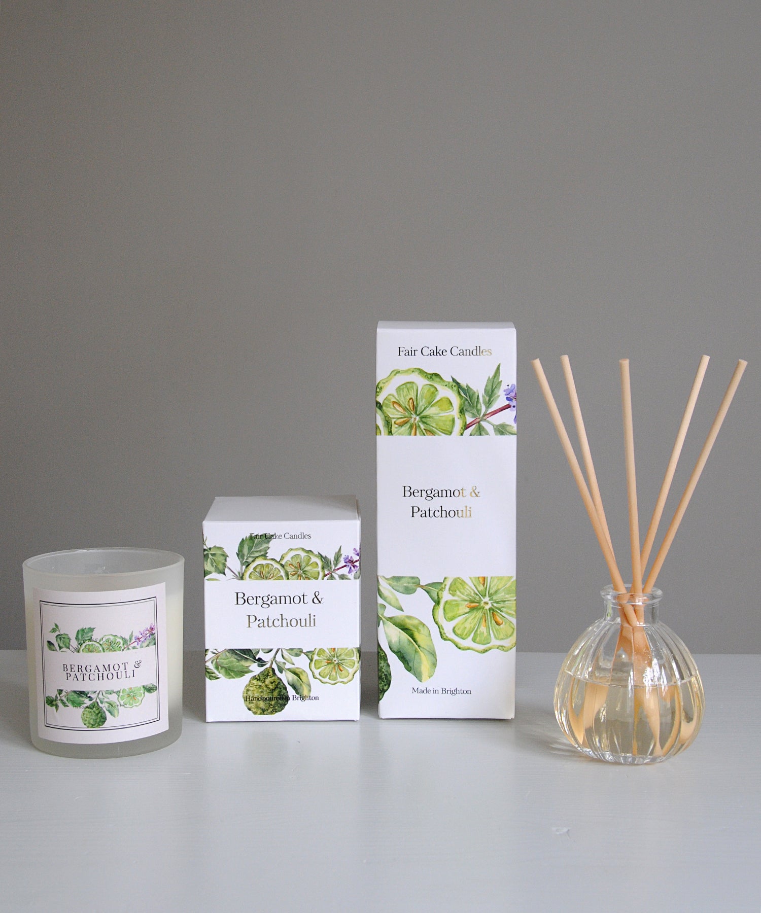 Bergamot and Patchouli candle, diffuser, and packaging on a gray background