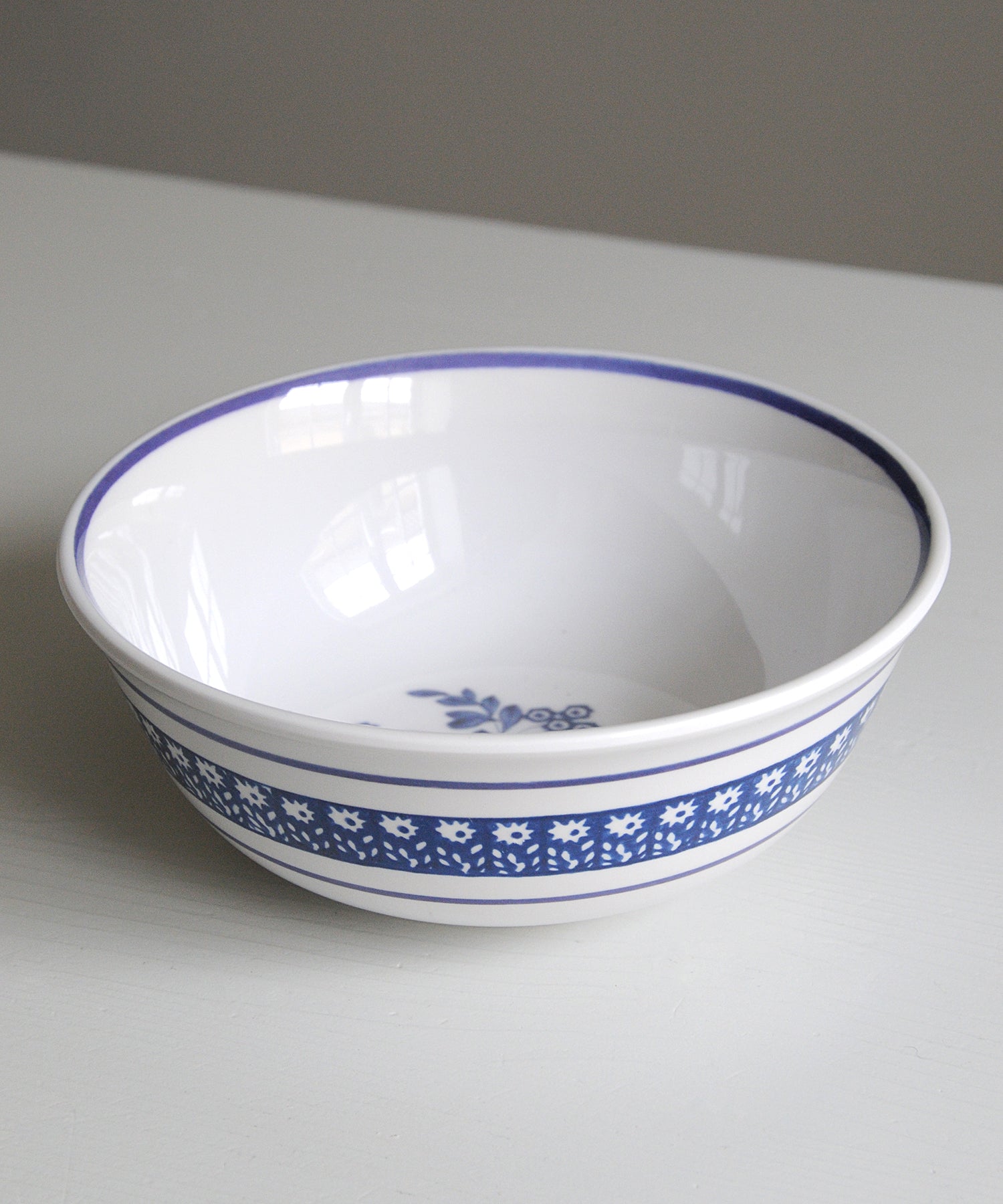 White melamine bowl with blue floral pattern on a grey background