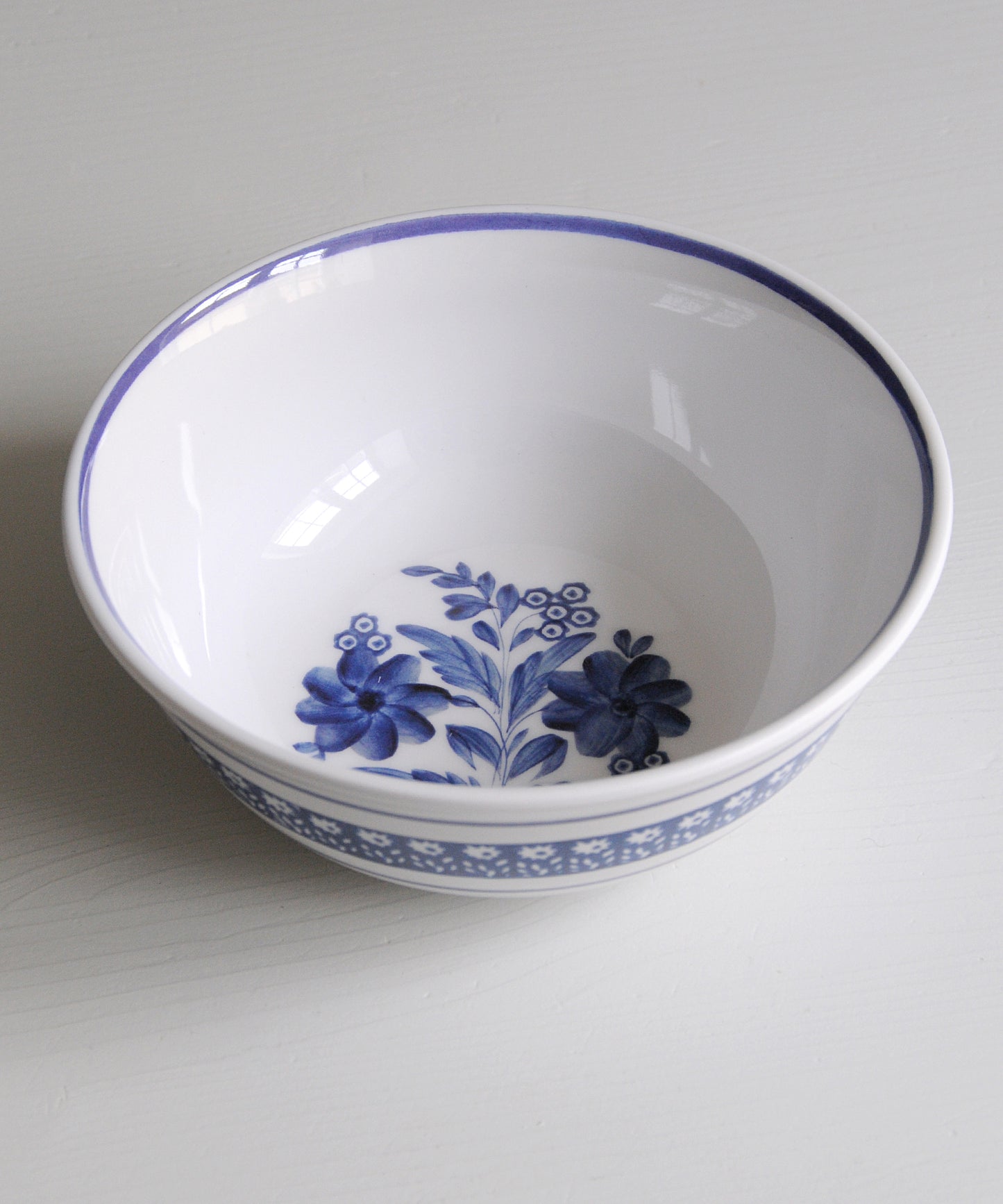 White melamine bowl with blue floral design on a white background