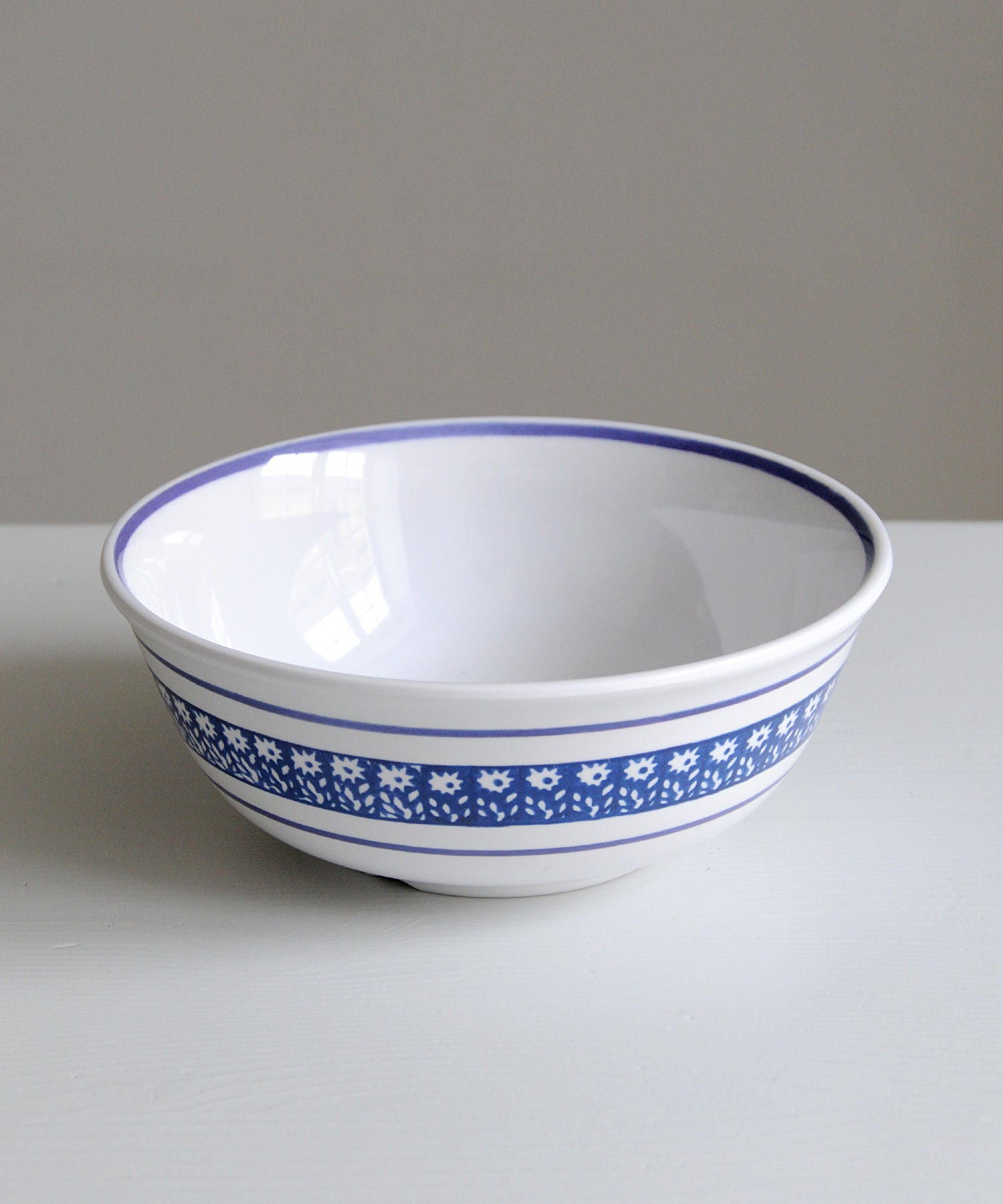 White melamine bowl with blue floral pattern on a gray background
