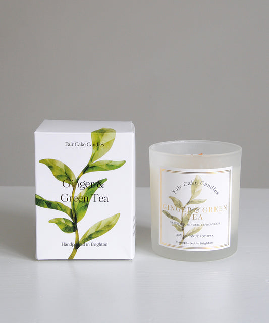 Frosted candle with 'Ginger & Green Tea' label next to its packaging on a gray background