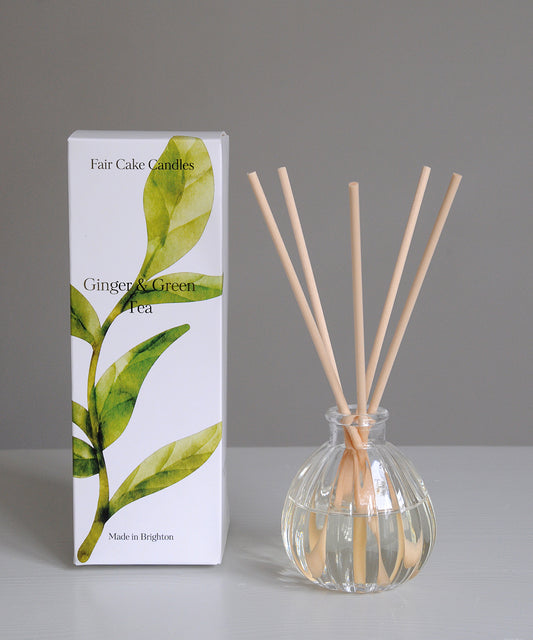 Diffuser with wooden sticks and packaging labeled 'Fair Cake Candles' on a gray background