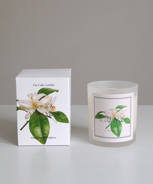 Frosted candle with floral label and packaging on a gray background