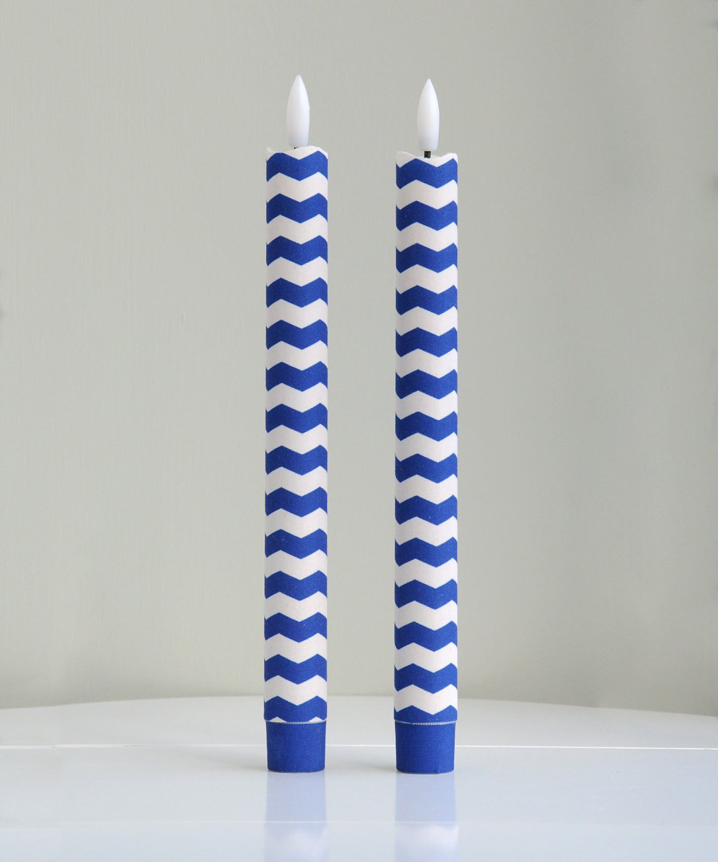 Two blue and white chevron patterned candles 