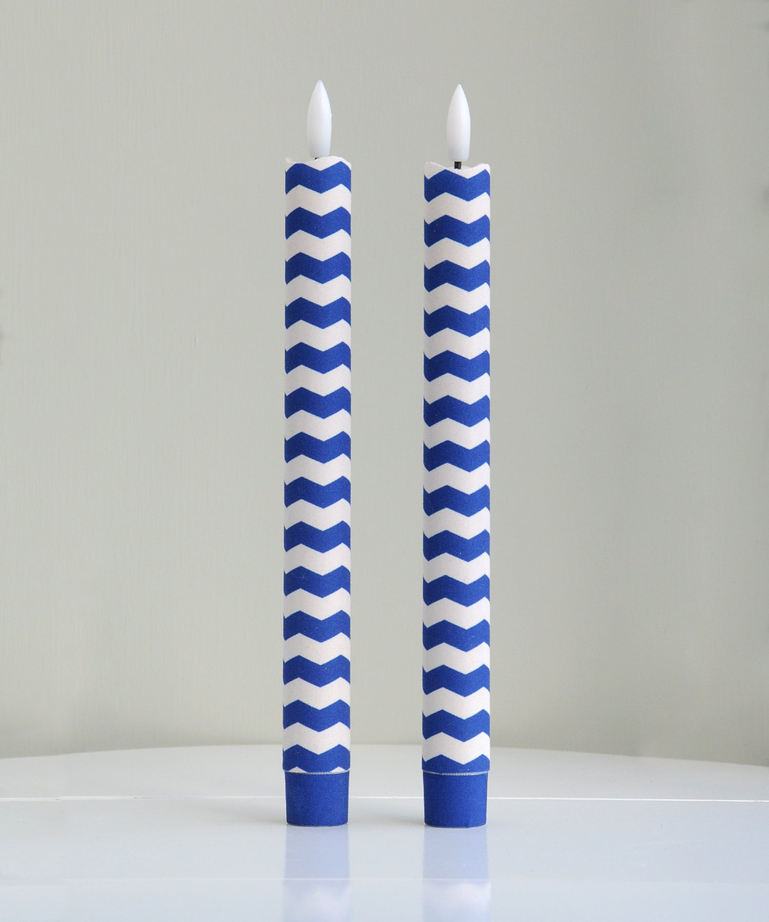 Two blue and white chevron patterned candles 