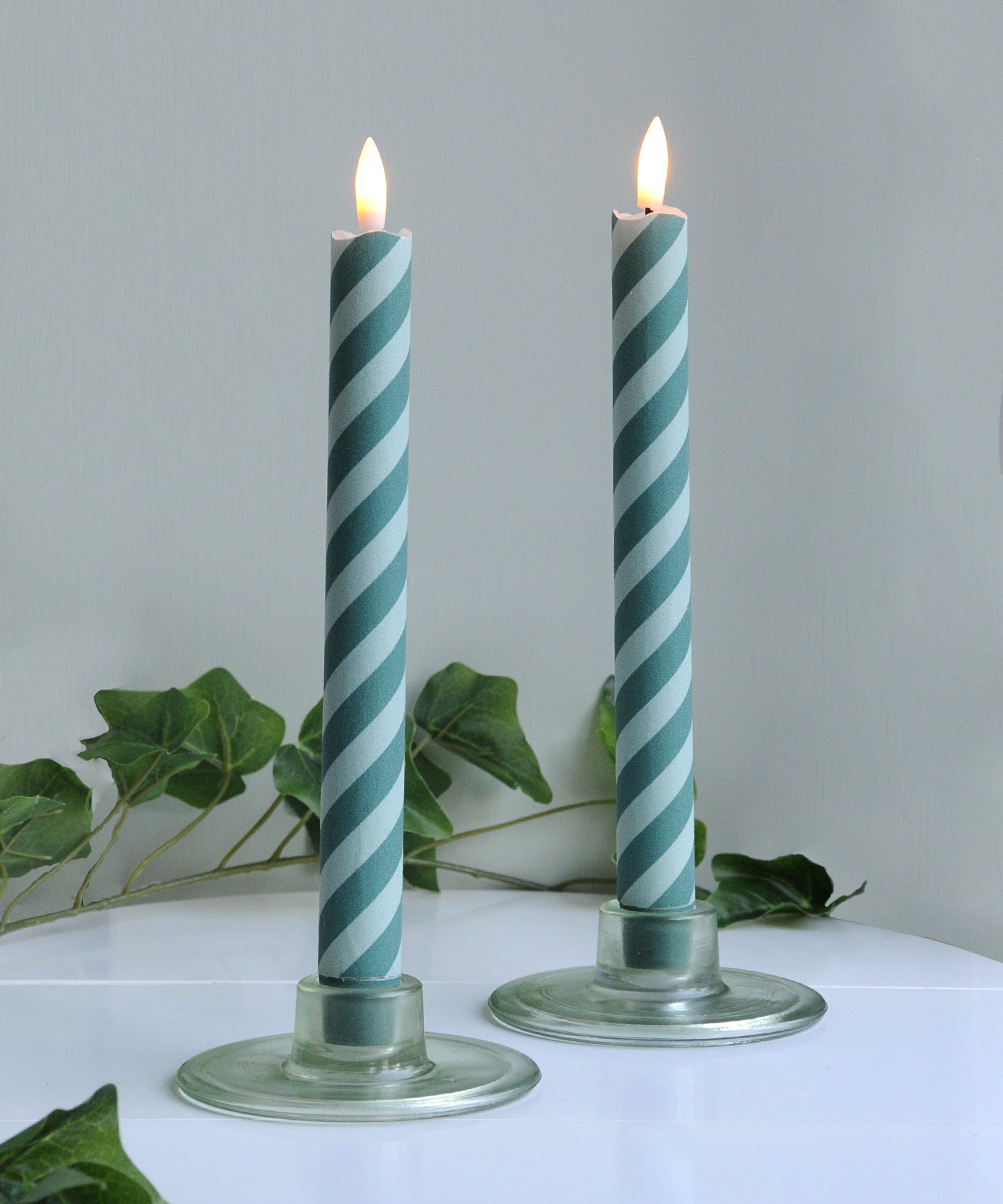 Two striped candles in glass holders .