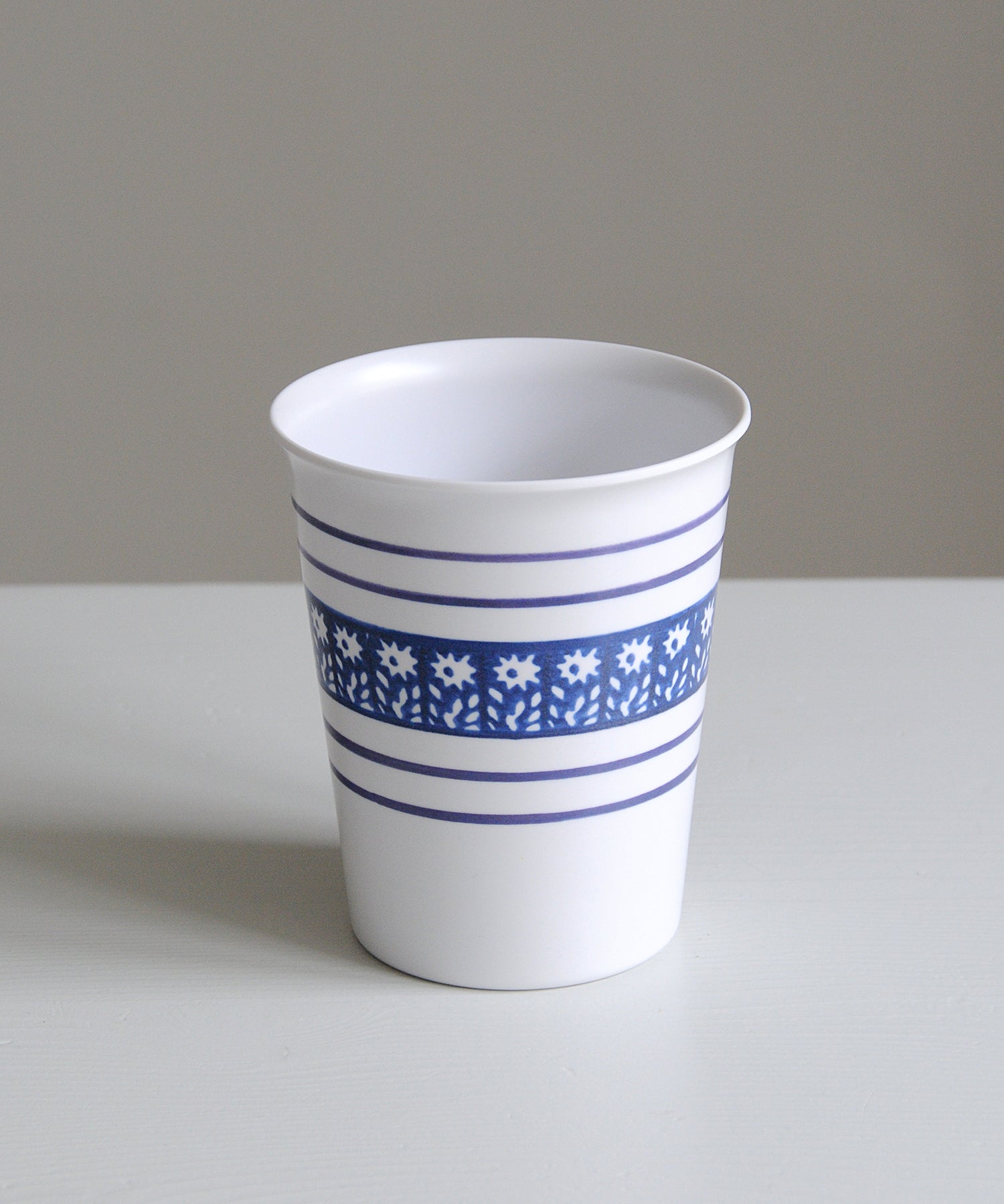 White cup with blue floral pattern on a gray background