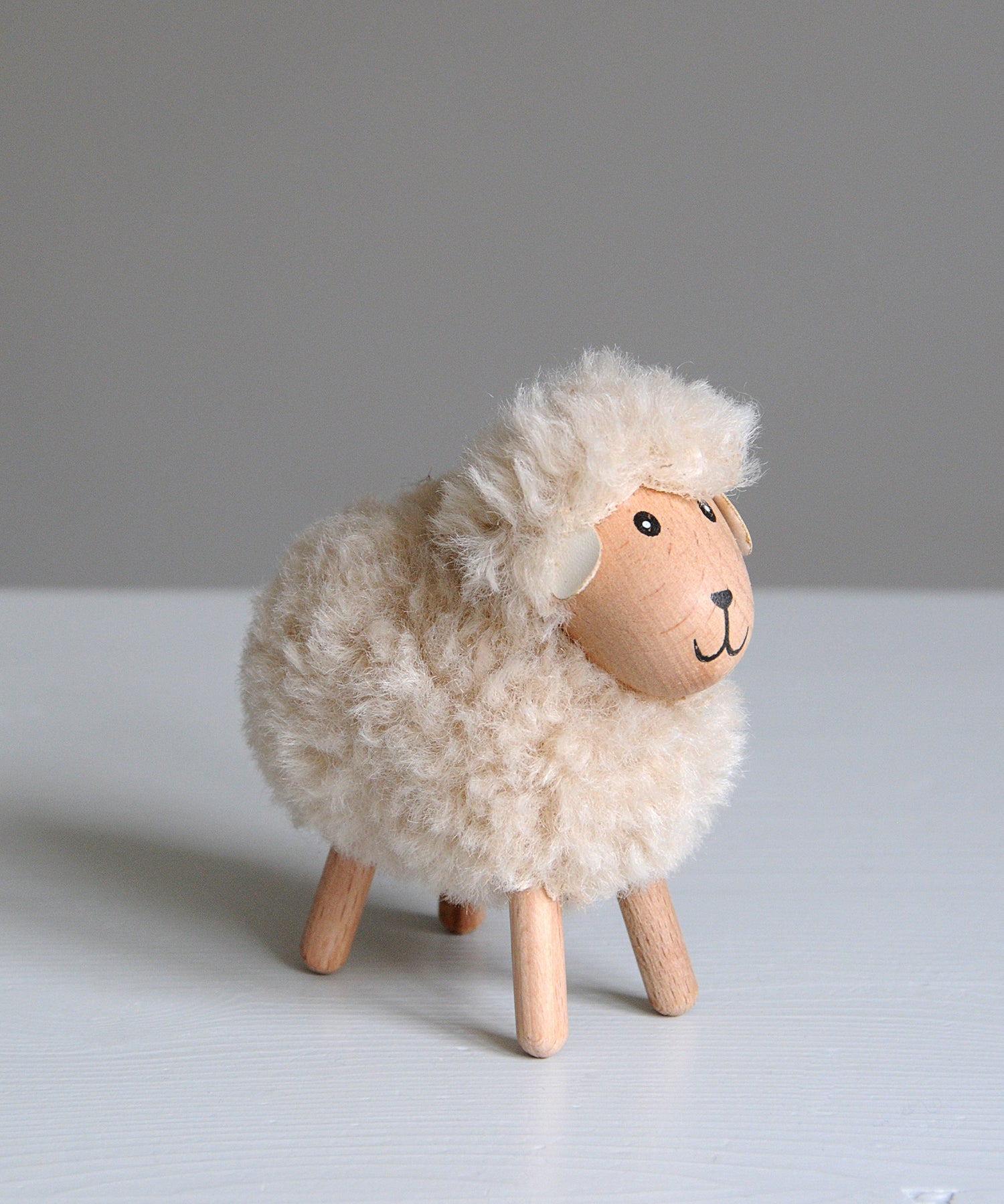Toy sheep with fluffy white wool on a gray background